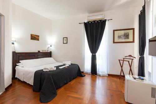 卡利亚里卡斯特伦旅馆的一间卧室配有一张带黑色窗帘的床,铺有木地板