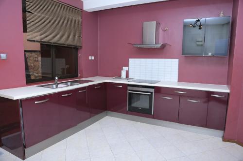 NamugongoRugsResidence的厨房设有紫色墙壁、水槽和炉灶。