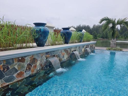 维多利亚Phoenix Apartments的三个蓝色花瓶坐在游泳池旁边的墙上
