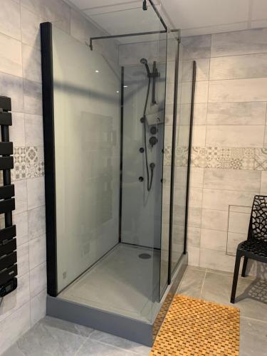 克卢尼La Maison Clémenso的一个带椅子的浴室内的玻璃淋浴间