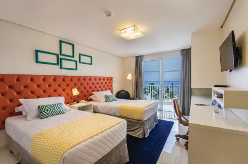 瓜鲁雅Doral Guarujá的酒店客房设有两张床和电视。