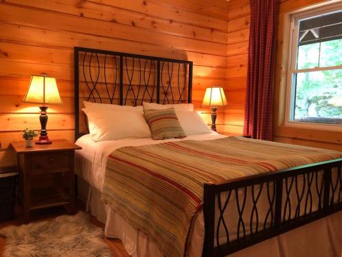 Val-des-LacsQuiet, cozy and comfortable chalet的一间卧室配有一张床、两盏灯和一个窗户。
