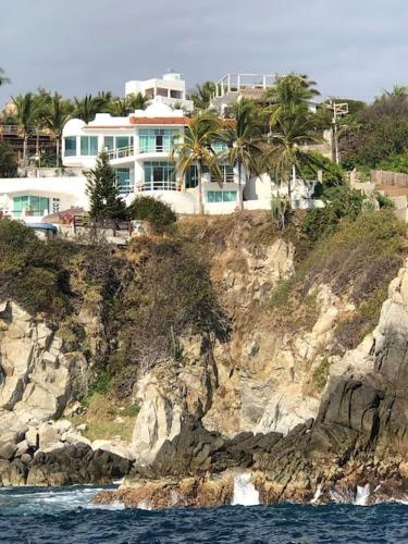 安赫尔港Hermosa Villa con alberca infinita Playa Zipolite的岩石山顶上的一个大房子
