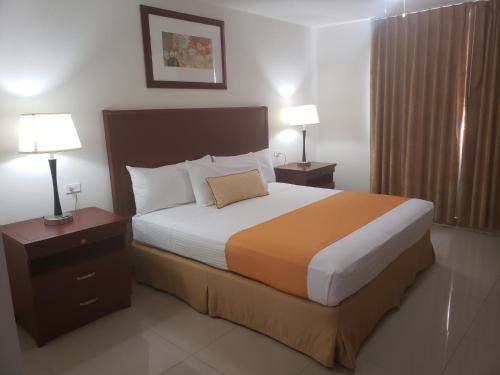 恩塞纳达港Hotel Presidente的一间卧室配有一张大床,设有两个床头柜和两盏灯