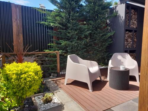 蓬塔德尔加达2Azores With Comfort and Style的木制甲板上配有两把白色椅子的庭院