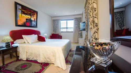 舍夫沙万帕拉多尔酒店的一间卧室,卧室内配有一张床和一张红色椅子