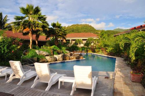 拉罗汤加落日度假村的一个带白色椅子的游泳池以及一座房子