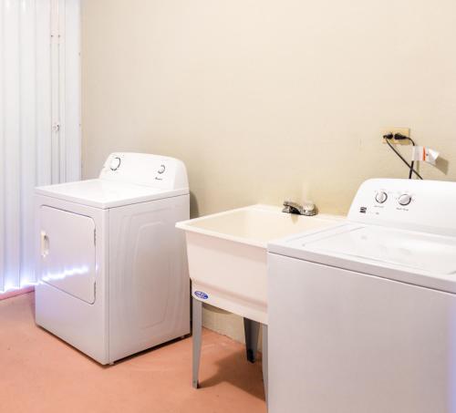 塔穆宁花园别墅酒店的白色洗衣房配有水槽和洗衣机