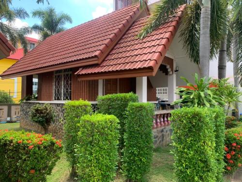 甘烹碧Bunraksa Resort的一座有红色屋顶和灌木的房子