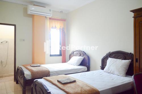 MojosongoPKPN Syariah Boyolali Mitra RedDoorz的酒店客房设有两张床和窗户。