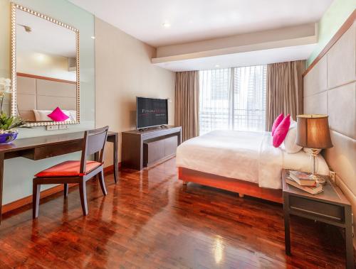 曼谷西隆富丽萨通酒店的酒店客房配有一张床、一张书桌和一台电脑