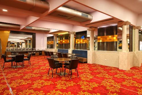 孟买Hotel Mumbai House Juhu, Santacruz West, Mumbai的一间铺有红地毯并配有桌椅的用餐室