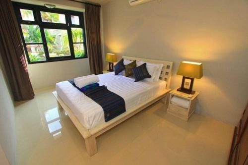 库塔5 Bedroom Holiday Villa - Kuta Regency B8的一间卧室设有一张大床和两个窗户