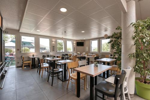 尤塞克B&B HOTEL Brive-la-Gaillarde的餐厅设有桌椅和窗户。