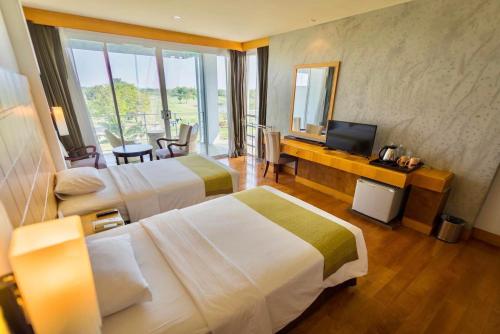 佛统Uniland Golf & Resort的酒店客房设有两张床和电视。