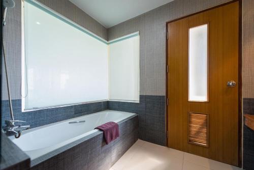 佛统Uniland Golf & Resort的带浴缸的浴室和窗户。
