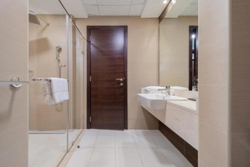 迪拜EDEN'S Homes & Villas - Sparkle Tower的浴室设有2个盥洗盆、淋浴和镜子。