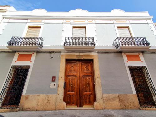 TurísCASA BAUTISTA TURIS的白色的建筑,设有木门和两个阳台