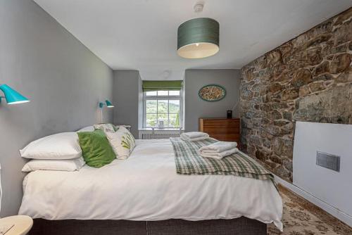 多尔盖罗Dolgellau Townhouse 2 Minutes to Town & Mountains的一间卧室设有一张大床和石墙