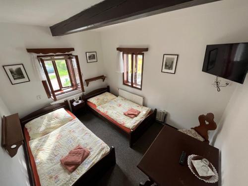 耶什赫维采Penzion Dřevák的客房设有两张床、一张桌子和一台电视机。