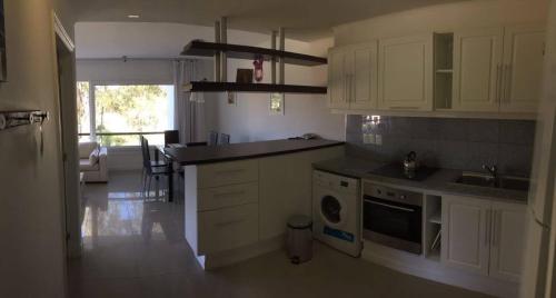 埃斯特角城Green Park Hermosos Apartamentos Vista al Lago的厨房配有白色橱柜、水槽和洗碗机。