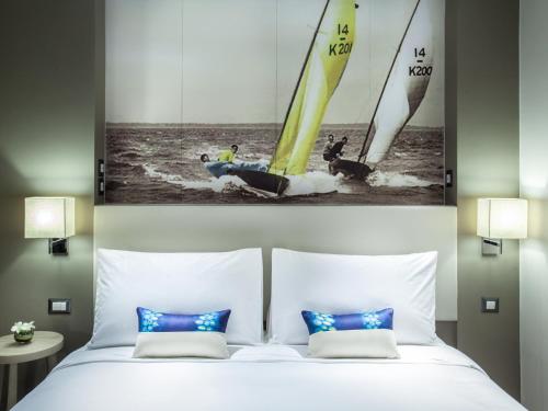 芭堤雅市中心芭堤雅美居海洋度假酒店的一间卧室,配有一张床,水中设有两艘帆船