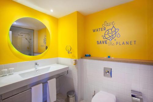 英格兰海滩Abora Catarina by Lopesan Hotels的浴室设有黄色的墙壁、水槽和镜子