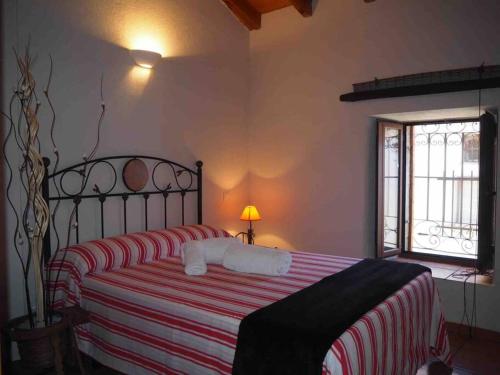 阿维拉Casa Rural El Guindo的一间卧室配有一张带红白条纹毯子的床