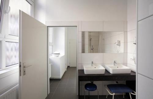 柏林胡腾帕拉斯特酒店的白色的浴室设有两个盥洗盆和镜子