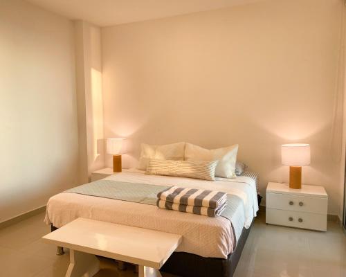 卡塔赫纳Apartamento en Cartagena con vista al mar的一间卧室配有一张带两盏灯和一张桌子的床。