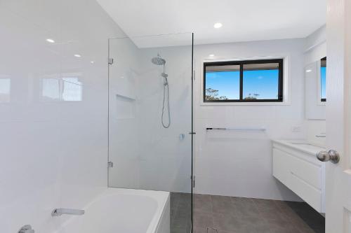 安特兰斯Lakeside Tranquillity的带淋浴和盥洗盆的白色浴室