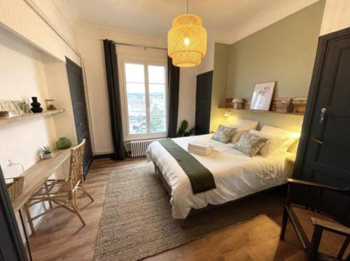 维希Vichy : Le 5e - Appartement design dans un ancien palace的一间卧室配有一张床、一张书桌和一个窗户。