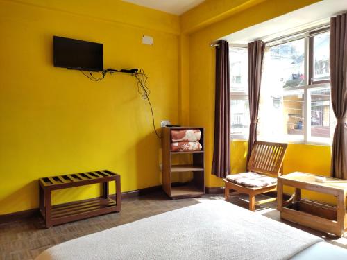 大吉岭Hotel Mhelung的黄色的房间,在黄色的墙上配有电视