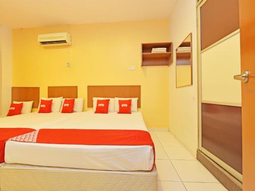 马六甲OYO 582 Hotel Walk Inn的一间卧室配有一张带红色枕头的大床