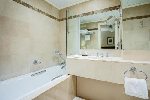 巴黎Hotel Royal Saint Honore Paris Louvre的带浴缸、水槽和镜子的浴室