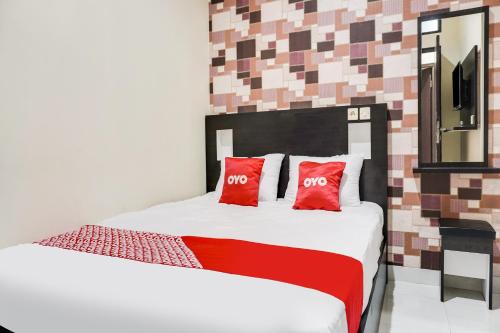 加拉旺OYO 91646 fio colombus residence的一间卧室配有一张带两个红色枕头的床