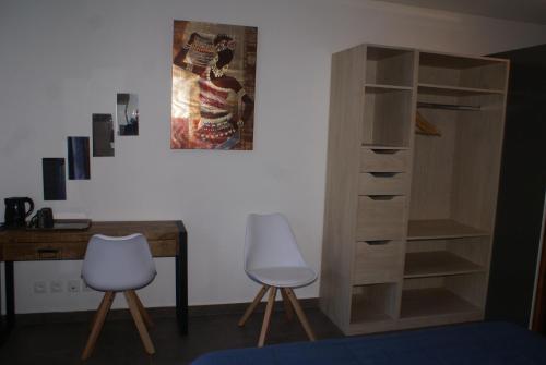 卡夫尔高原Chambre d’hôte Les Quatres Saisons的一张桌子和两张椅子,旁边是木制书柜