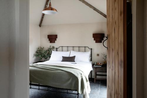 米尔敦马尔贝Gate Lodge@White Strand的一间卧室配有一张带白色床单和一盏灯的床。