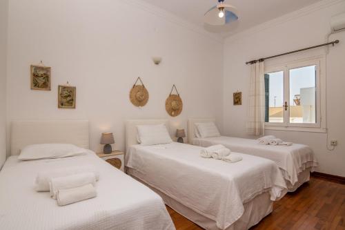 纳克索乔拉My Home in Naxos的客房设有三张床、白色床单和窗户。