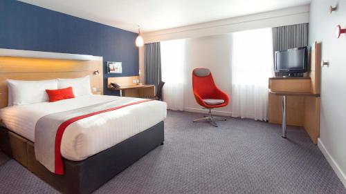 伦敦快捷假日伦敦莱姆豪斯酒店的酒店客房,配有一张床和一张红色椅子