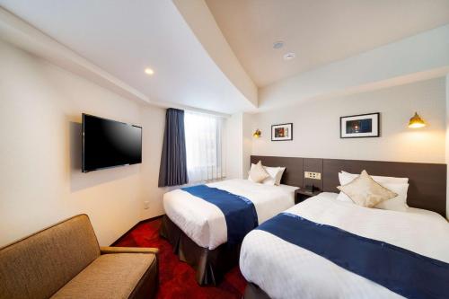 横滨Best Western Hotel Fino Shin-Yokohama的酒店客房,设有两张床和一张沙发