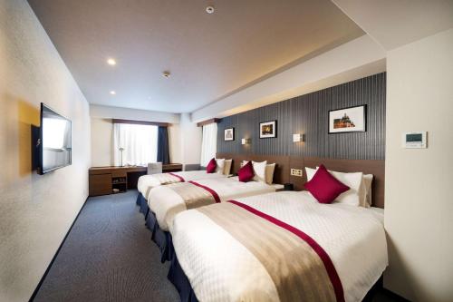 福冈Best Western Plus Fukuoka Tenjin-minami的酒店客房,配有3张带红色枕头的床