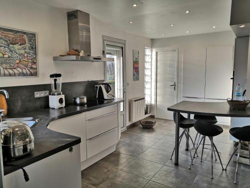 Eaucourt-sur-SommeB&B Egloff的厨房配有白色橱柜和带凳子的桌子