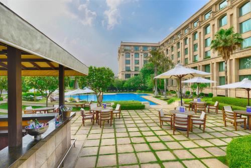 新德里新德里酒店的酒店庭院设有桌椅和游泳池。