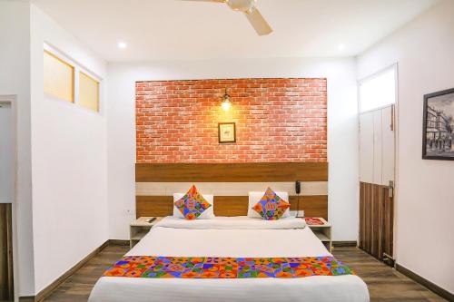 古尔冈FabHotel Aravali Suites的砖墙前设有一张大床的卧室
