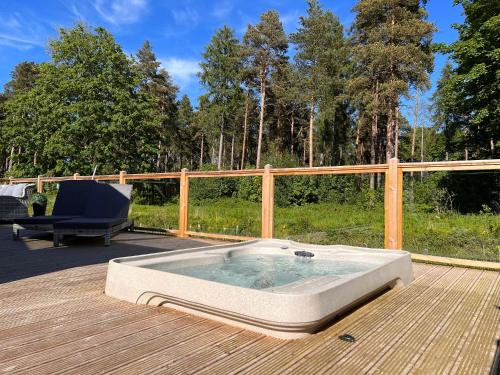 约克Hollicarrs - Dragonfly Lodge的木制甲板上的热水浴池和椅子