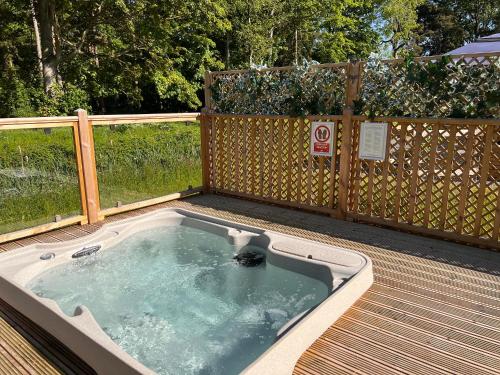 约克Hollicarrs - Dragonfly Lodge的甲板上的热水浴池,设有围栏