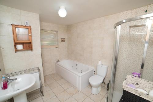 Torpys Cross RoadsBallygown Cottage的带浴缸、卫生间和盥洗盆的浴室