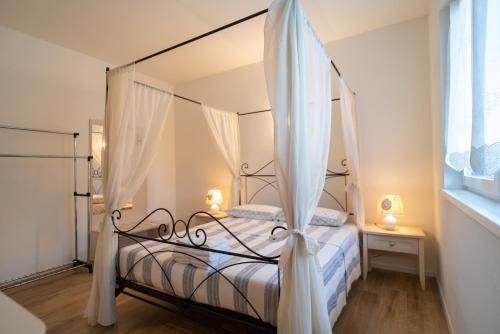 泰尔拉戈La casa di Terlago的卧室配有带白色窗帘的天蓬床
