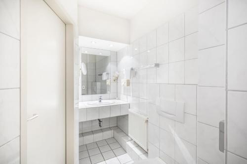门兴格拉德巴赫Hotel Elisenhof Mönchengladbach的白色的浴室设有水槽和镜子